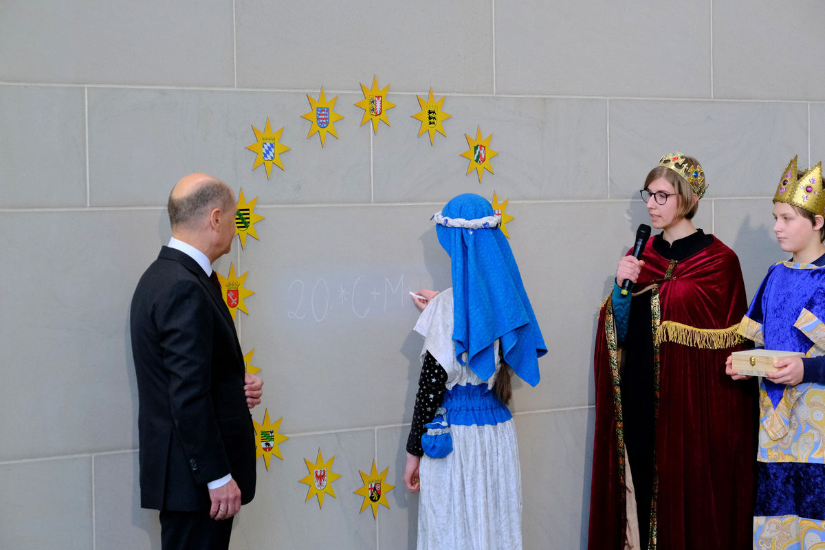 Die Sternsingerinnen und Sternsinger Ruth (15), Josef (13), Paula (15) und Isabella (13) aus der Gemeinde St. Mathilde in Quedlinburg (Bistum Magdeburg) sprechen den Segensspruch, Ruth schreibt den Segen an. Foto: Ralf Adloff/ Kindermissionswerk